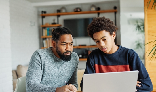 Father and son looking at the laptop.