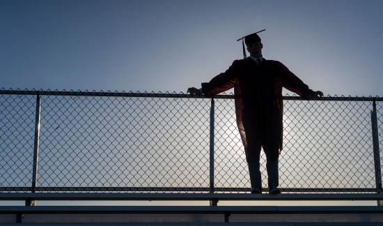 high school graduate standing at the top of the bleachers.
