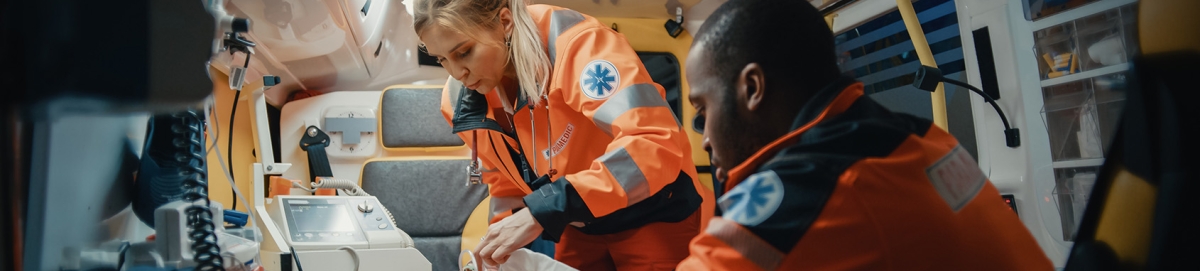 Female and male paramedic inside ambulance attending a person.